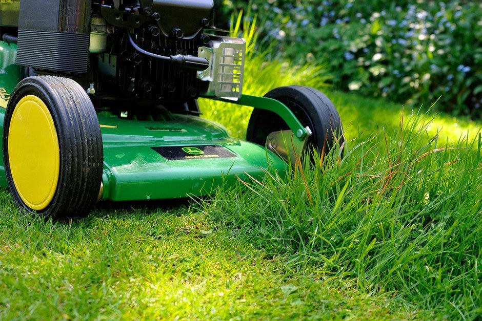 A green lawn mower parked on a well-maintained patch of grass.