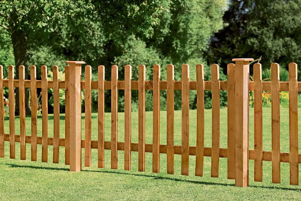 A wooden fence encloses a yard, complemented by several tall trees, enhancing the natural beauty of the area.